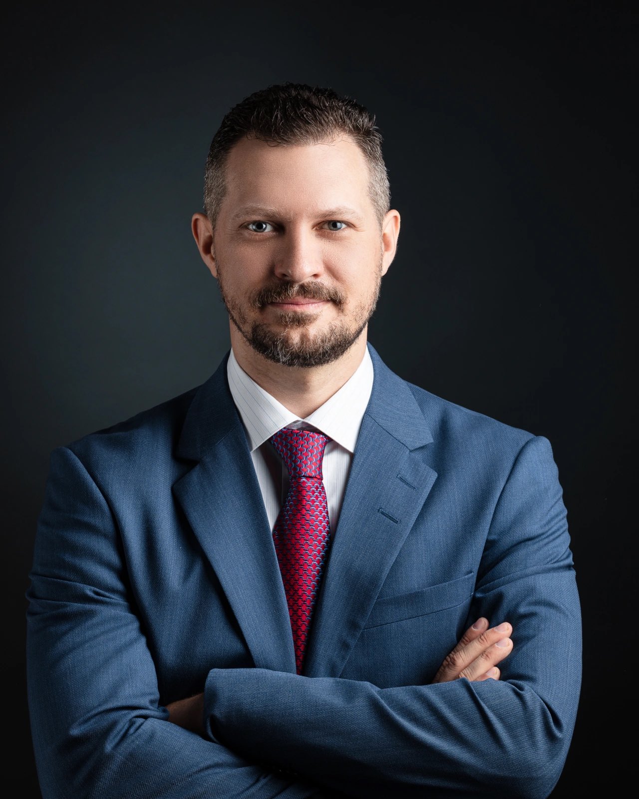 Sascha Getzinger, Principal of Getzinger & Partners, in a dark suit against a charcoal studio background